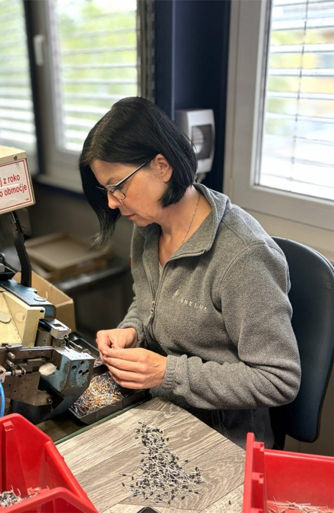A female production line operator assembling electronic lighting components at her workstation in the Ignelux factory.